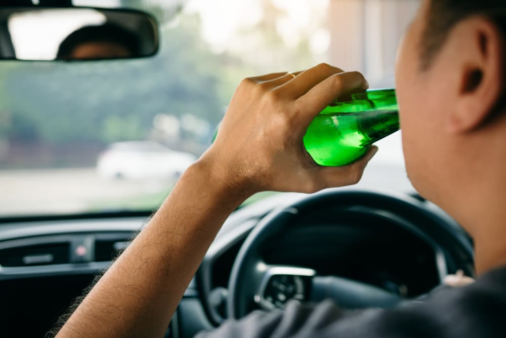 Two men are violating traffic laws by drinking beer while driving.