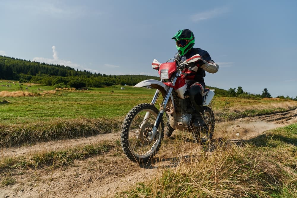 A skilled motocross rider thrillingly navigating a challenging off-road forest trail on their motorcycle.






